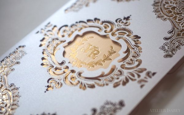 Un perfecto ejemplo que combina una invitación en dorado con estampado en letterpress dorado dentro de un sobre blanco con elaborado diseño en corte láser. Una creación de Atelier Isabey