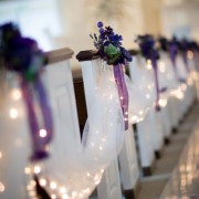 Como decorar el pasillo central de la ceremonia de bodas. Drapeado en tul blanco, mini-luces blancas, arreglos florales en seda morados con hojas verdes y cintas violetas con lazos. Pristine Chapel, Sacramento, CA.