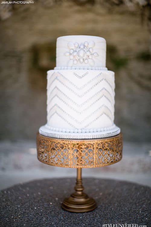 Great Gatsby inspired wedding cake. White wedding cake with silver sparkle on a vintage gold cake stand.