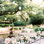 A pink and grey-themed wedding at the Houston Zoo with a gray table runner trimmed with lace and pretty white flowers. Photo: Brides.