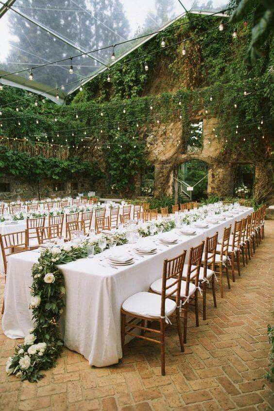 This venue's walls were already covered in ivy. The creation of a coherent look was achieved by adding greenery and white flower garlands as table runners. So pretty.