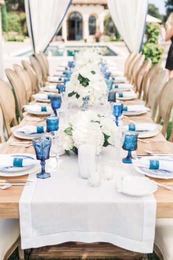 Una mesa de banquete de bodas al aire libre en beige, blanco y azul. Detalle de porta servilletas al tono. Valorie Darling Photography.