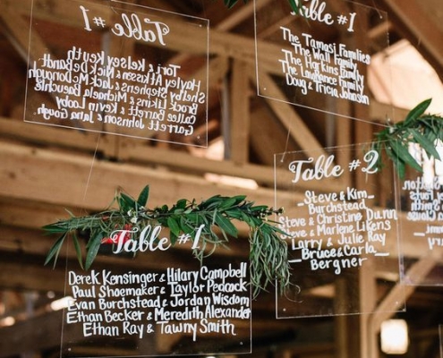 Amazing and original hanging acrylic seating charts with greenery.