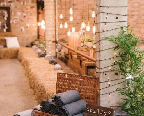 We love the rustic meets industrial decor vibe. Bales of hay, exposed brick and hanging Edison bulbs. Blankets in a basket favors make loving winter wedding ideas.